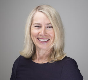 Portrait photo of smiling woman in navy top with shoulder-length dark blond hair